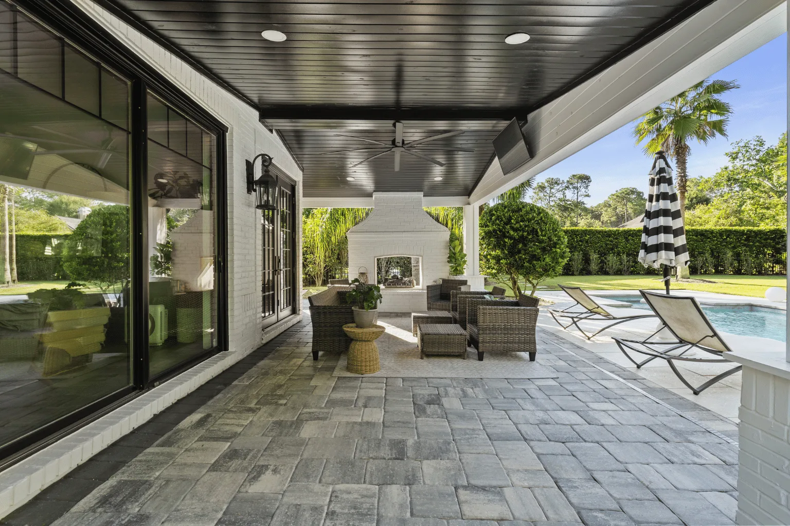 Covered paver patio installation with fireplace and poolside access by Jax Pavers in Jacksonville FL