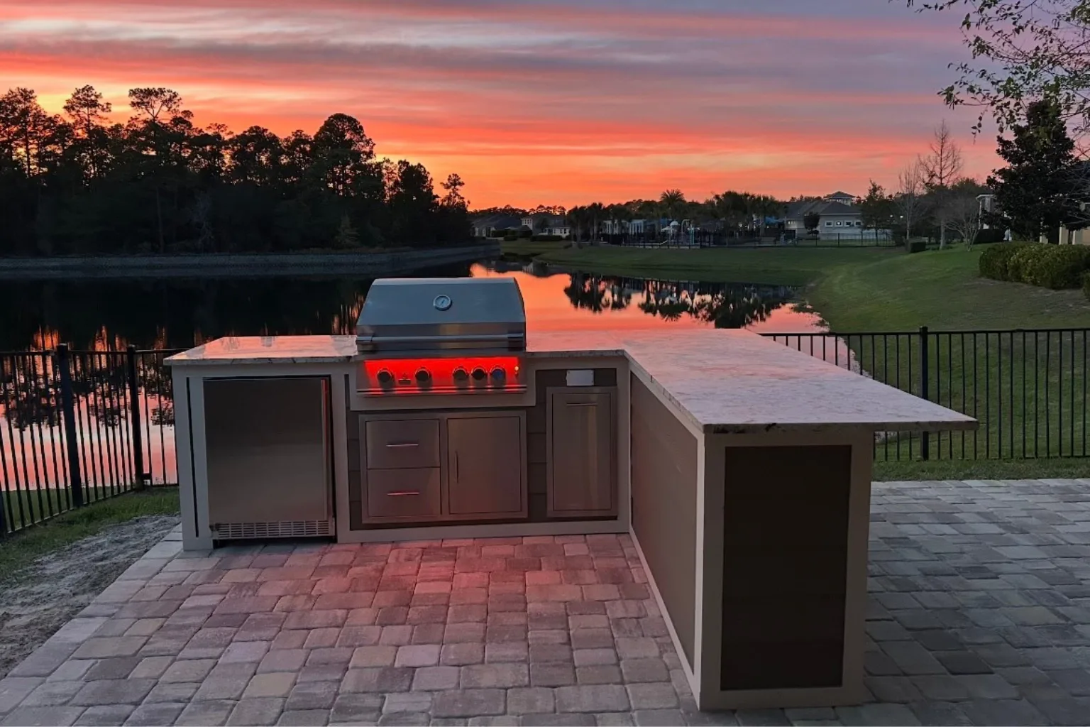 Waterfront outdoor kitchen island with built-in grill and LED lighting at sunset by Jax Pavers in Jacksonville FL