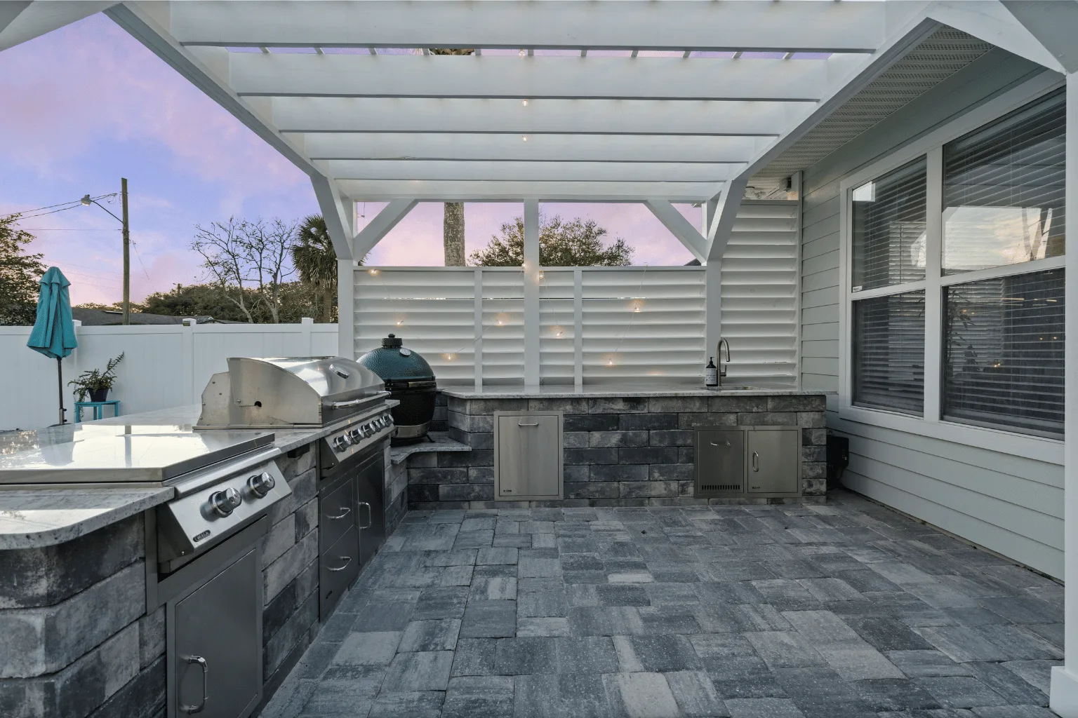 L-shaped outdoor kitchen installation with pergola, grill, and smoker by Jax Pavers in Jacksonville FL