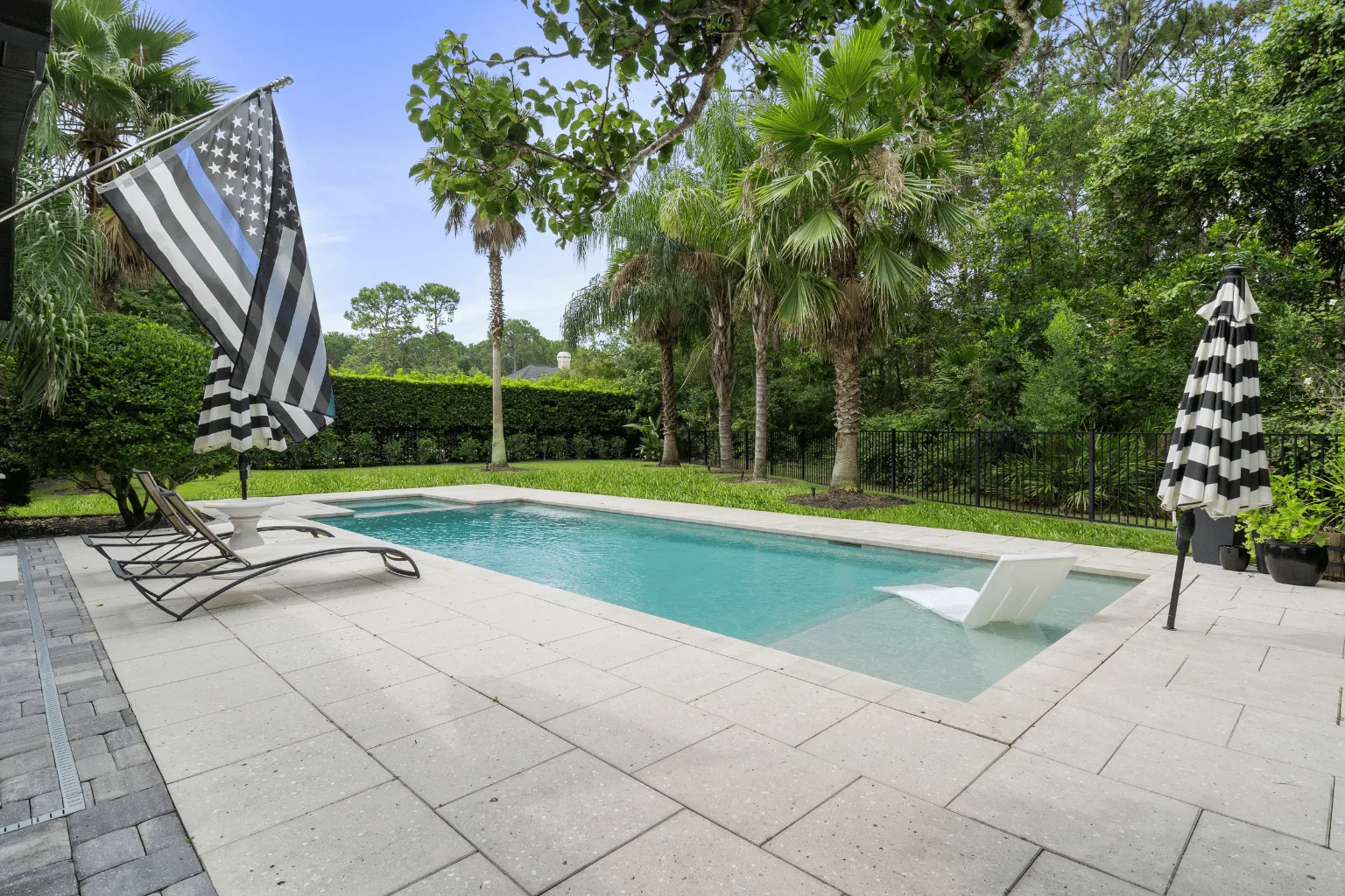 Paver pool deck installation with sun shelf and tropical landscaping by Jax Pavers in Jacksonville FL