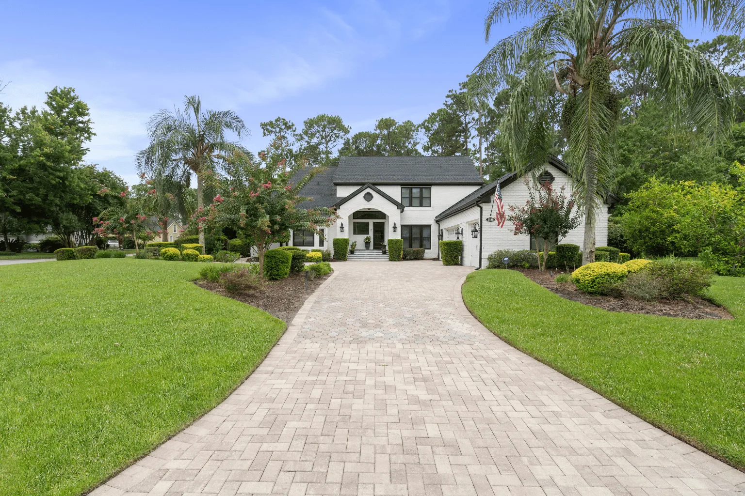 Curved paver driveway installation through palm-lined landscaping by Jax Pavers in Jacksonville FL
