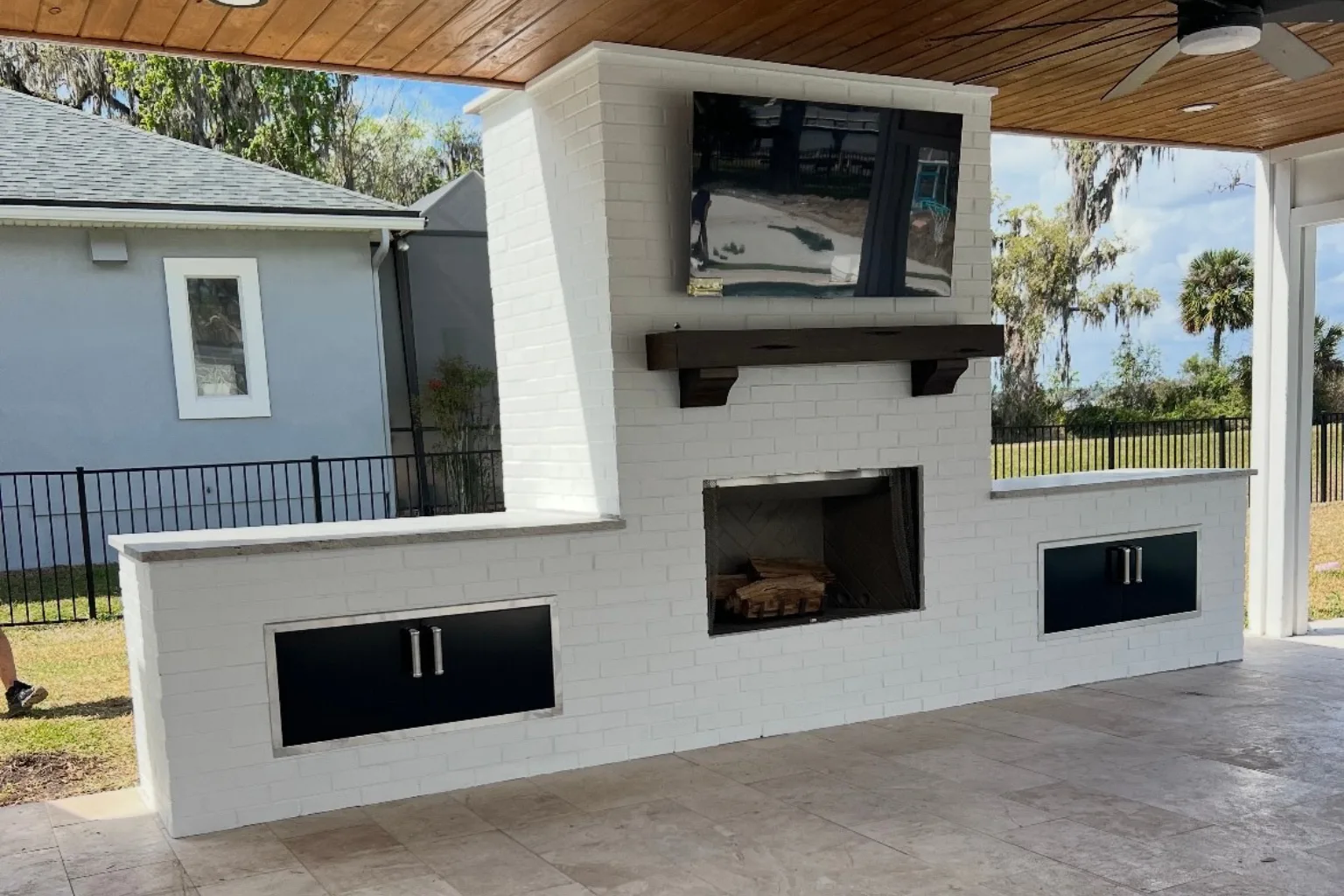 Covered patio with outdoor fireplace, TV, and built-in storage cabinets by Jax Pavers in Jacksonville FL