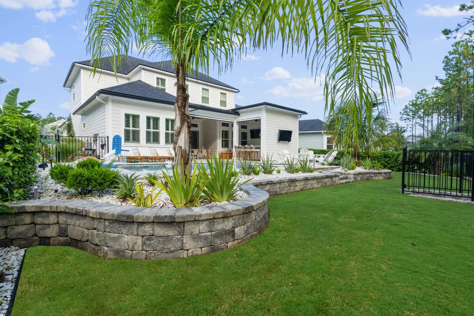 Paver pool deck and retaining wall installation with tropical landscaping by Jax Pavers in Jacksonville FL
